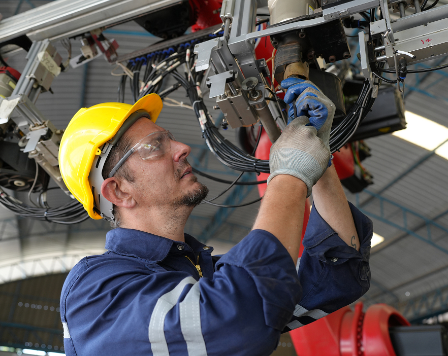 mantenimiento-industrial-robotica Técnico realizando mantenimiento en un brazo robótico industrial con equipo de seguridad.