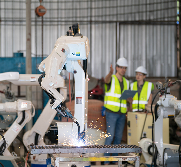 Robot de soldadura automatizada en una fábrica con ingenieros supervisando el proceso.